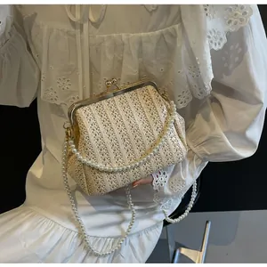Detail of white woven evening bag with vintage gold clasp and elegant pearl handle