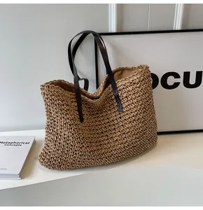 Detalle macro del bolso tote de paja trenzada con asas de cuero sintético marrón y forro