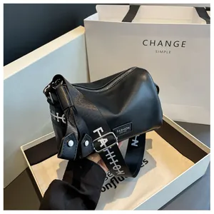 Detail of black pebbled leather pillow bag with a sporty branded wide strap in a gift box