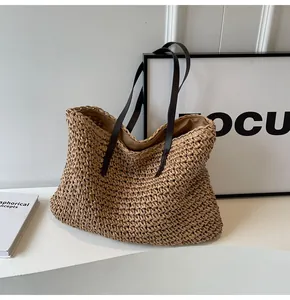 Detalle de textura de bolso tote de paja tejida y tirantes finos marrones en la base