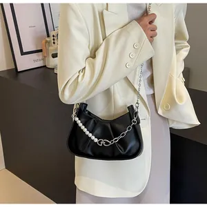 Detail of black pleated cloud bag with elegant pearl and silver metal chain strap