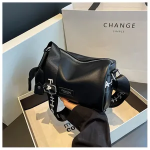 Detail of black lychee grain leather cylinder bag with stylish wide fashion letter strap