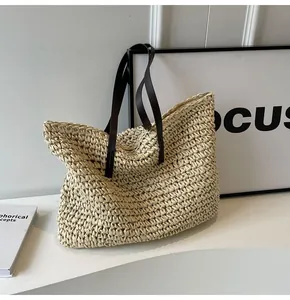 Detalle del bolso tote de paja trenzada con asas de cuero marrón y costuras de calidad