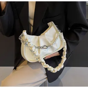 Detail of white pleated cloud bag with pearl chain strap and soft leather texture