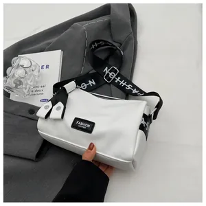 Detail of white lychee leather cylinder bag with fashion letter wide strap on grey blazer