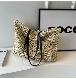 Detalle del bolso tote de paja tejida con asas de cuero marrón y cierre de cremallera