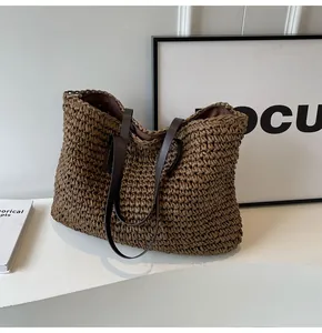 Detalle del bolso tote trenzado marrón oscuro con asas de cuero y textura tejida