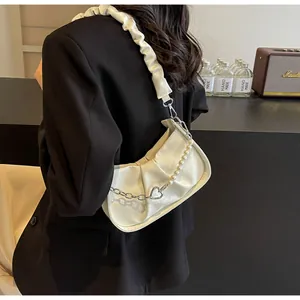 Detail of off-white pleated cloud bag featuring pearl chain and heart pendant strap