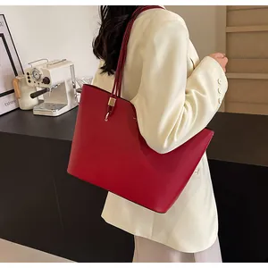 Detailed close-up of a large red leather tote bag with elegant gold hardware
