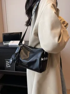Modern black leather cylinder crossbody bag with wide logo strap shown on a model