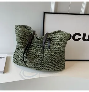 Vista detallada de la textura del bolso tote de paja verde y asas de cuero sintético marrón