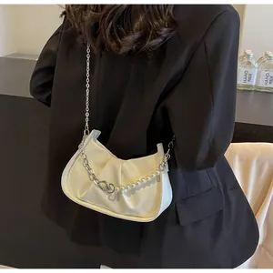 Close-up of creamy white ruched cloud bag with elegant pearl and silver chain strap detail