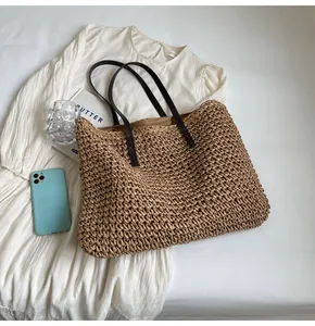 Vista plana del bolso tote de paja tejida con correas de cuero y accesorios de verano