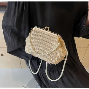 Detail of beige straw shell evening bag with pearl chains and vintage kiss-lock clasp
