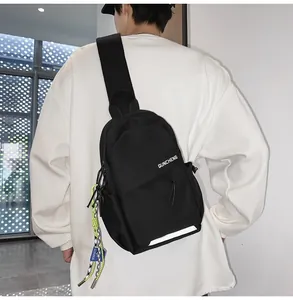 Detalle de bandolera negra con tira reflectante y cordón sobre una sudadera blanca