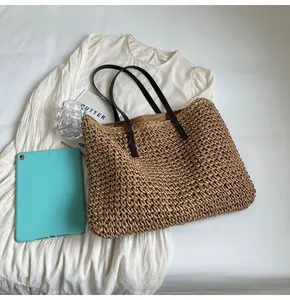 Vista superior de un gran bolso tote de paja tejida con asas de cuero marrón en vestido