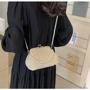 Detail of cream woven shell bag featuring elegant pearl straps and golden vintage clasp