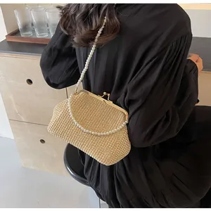 Detail of hand-woven straw bag featuring golden clasp closure and elegant pearl strap