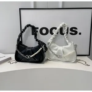 Detail showing ruched cloud bags in black and white with decorative pearl chain straps