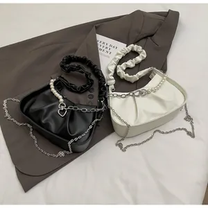 Detail view of ruched cloud bags in black and beige with pearl and chain handles