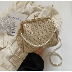 Detail of cream woven straw evening bag with gold metal clasp and pearl chain strap