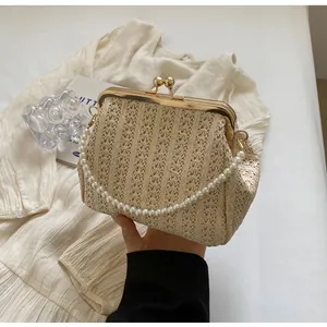 Detail of hand-woven straw bag with vintage gold kiss-lock and elegant pearl chain handle