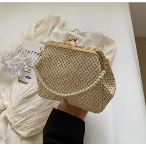 Close-up of woven beige clutch bag with pearl handle strap and golden metal clasp detail