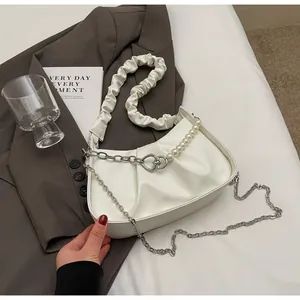 Detail view of white ruched cloud bag featuring silver chain and pearl strap decor
