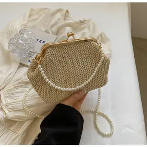 Detail of a beige woven shell clutch bag featuring a vintage kiss-lock and pearl strap