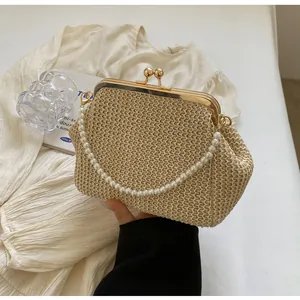 Detail of hand-woven straw bag featuring golden metal frame and large pearl chain handle
