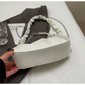 Detail of white ruched cloud bag with pearl strap and silver metal chain accessory