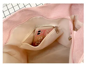 Détail du sac fourre-tout en velours rose montrant la poche zippée et la doublure