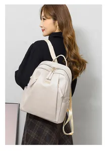 Detail of minimalist beige PU leather backpack with gold hardware and side pocket on model
