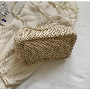 Detail shot of the woven straw texture and elegant pearl shoulder strap on this beige bag