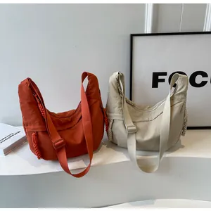 Detail view of crescent crossbody bags in orange and cream with thick nylon texture