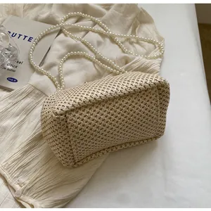 Detail of hand-woven beige bag featuring a luxury large pearl strap and fine straw texture