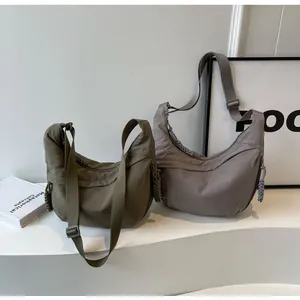 Detail of two nylon crescent bags in olive and taupe with woven zipper pulls
