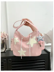 Détails de la texture velours de ce sac rose avec étoiles blanches et poche latérale