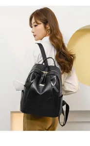 Detail of vintage black PU leather backpack with geometric texture and gold hardware