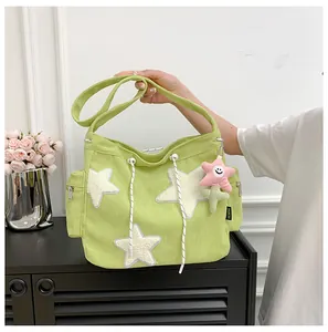 Détail du sac à bandoulière en velours vert avec étoiles et breloque fleur rose
