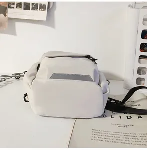 Detalle del bolso de pecho de nailon blanco crema con tira reflectante y hebilla ajustable