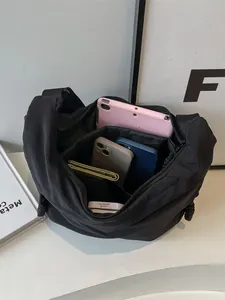 Black nylon crossbody dumpling bag showing spacious interior with tablet and gadgets
