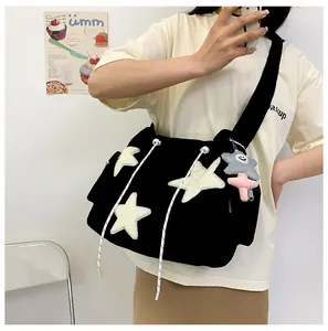 Vue détaillée du sac à bandoulière en velours côtelé noir avec étoile blanche et peluche