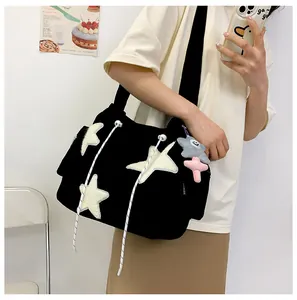 Détail du sac à bandoulière en velours noir avec étoiles en peluche et breloques décoratives