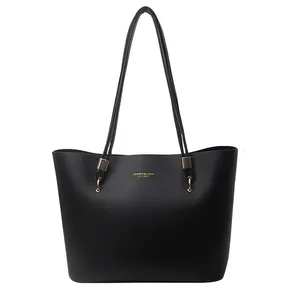Minimalist black faux leather tote bag with gold lettering and slim shoulder straps
