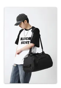 Model showing large black sports duffel bag with shoulder strap and side zipper pocket