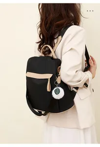 Détail du sac à dos noir résistant à l'eau avec bordure beige et breloque peluche