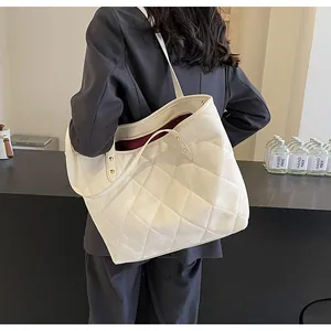 Detailed view of quilted tote bag featuring gold rivets and contrast red lining accents