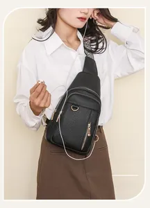 Detail of black pebbled leather chest bag with a geometric pattern strap and earphone hole