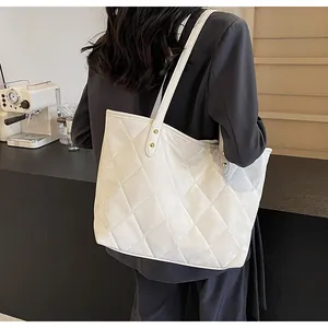 Detail of cream quilted tote bag with diamond stitching and reinforced handles